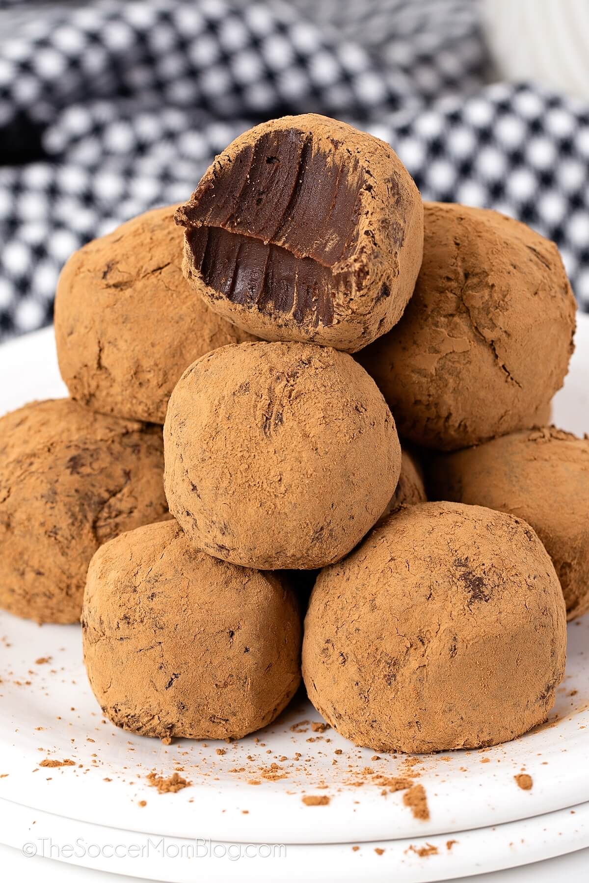 homemade chocolate truffles piled on a plate, one with a bite taken.
