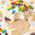 stack of 3 rice krispie treat squares, top one with M&Ms and a bite taken.