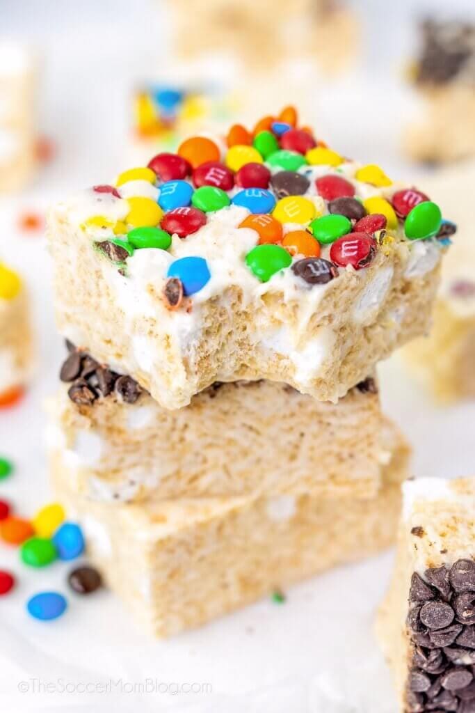 stack of 3 rice krispie treat squares, top one with M&Ms and a bite taken.