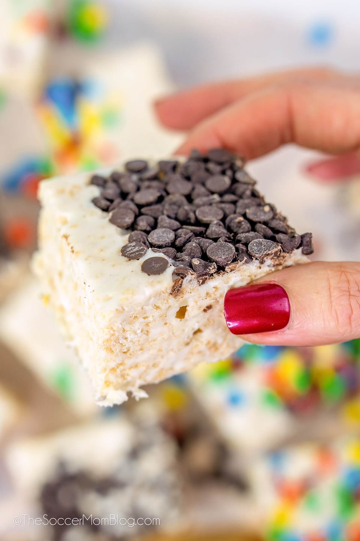 hand holding a rice krispie treat topped with mini chocolate chips.
