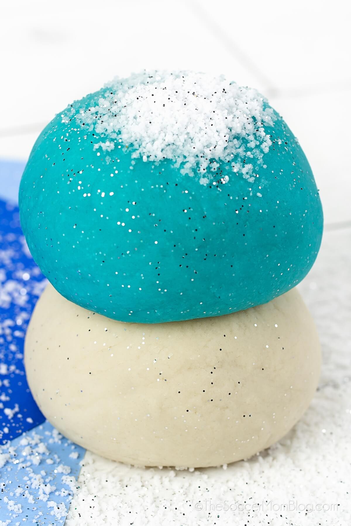 ball of blue playdough stacked on top of a ball of white playdough.