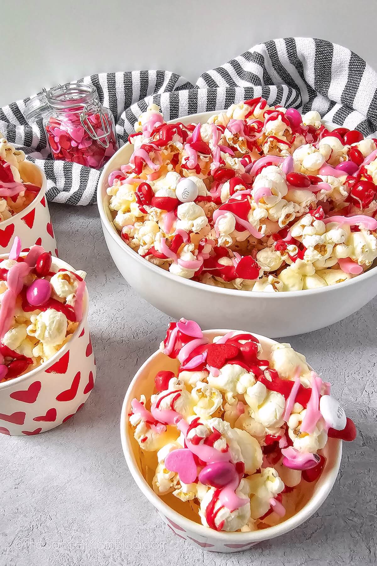candy coated Valentine' Day Popcorn, in a large serving bowl and three small cups.
