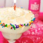 close up of a birthday margarita with lit candle.