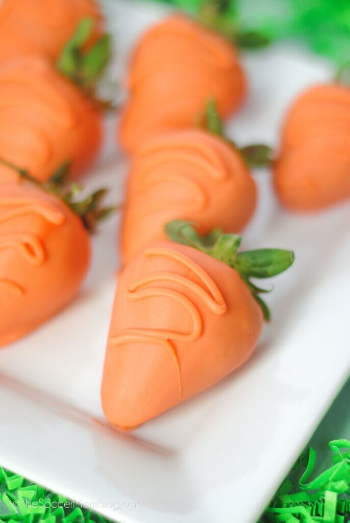plate of orange chocolate covered strawberries that look like carrots.