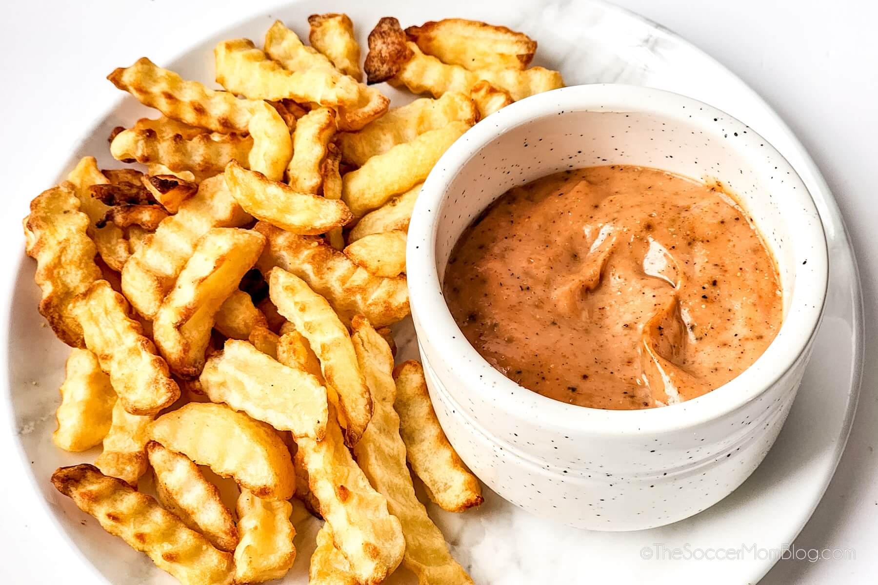Copycat Raising Cane's Dipping Sauce in ramekin with plate of French fries.