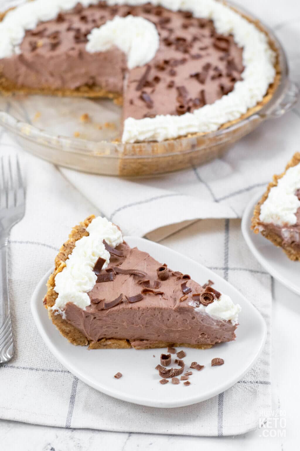 slice of chocolate pie with rest of pie in background.