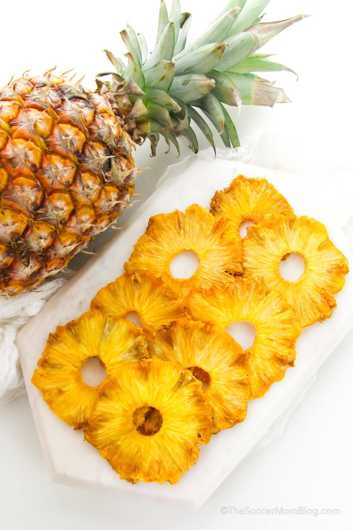 Oven dried pineapple slices on a white serving tray.