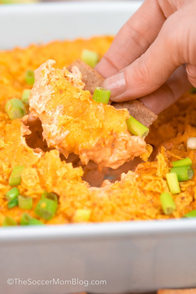scooping up a buffalo chicken dip with a cracker.