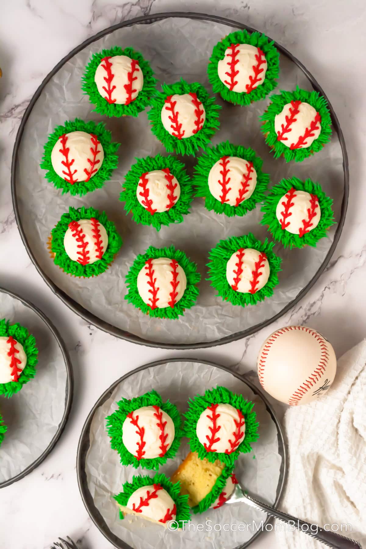 Baseball themed Cupcakes on serving trays with one cut in half.