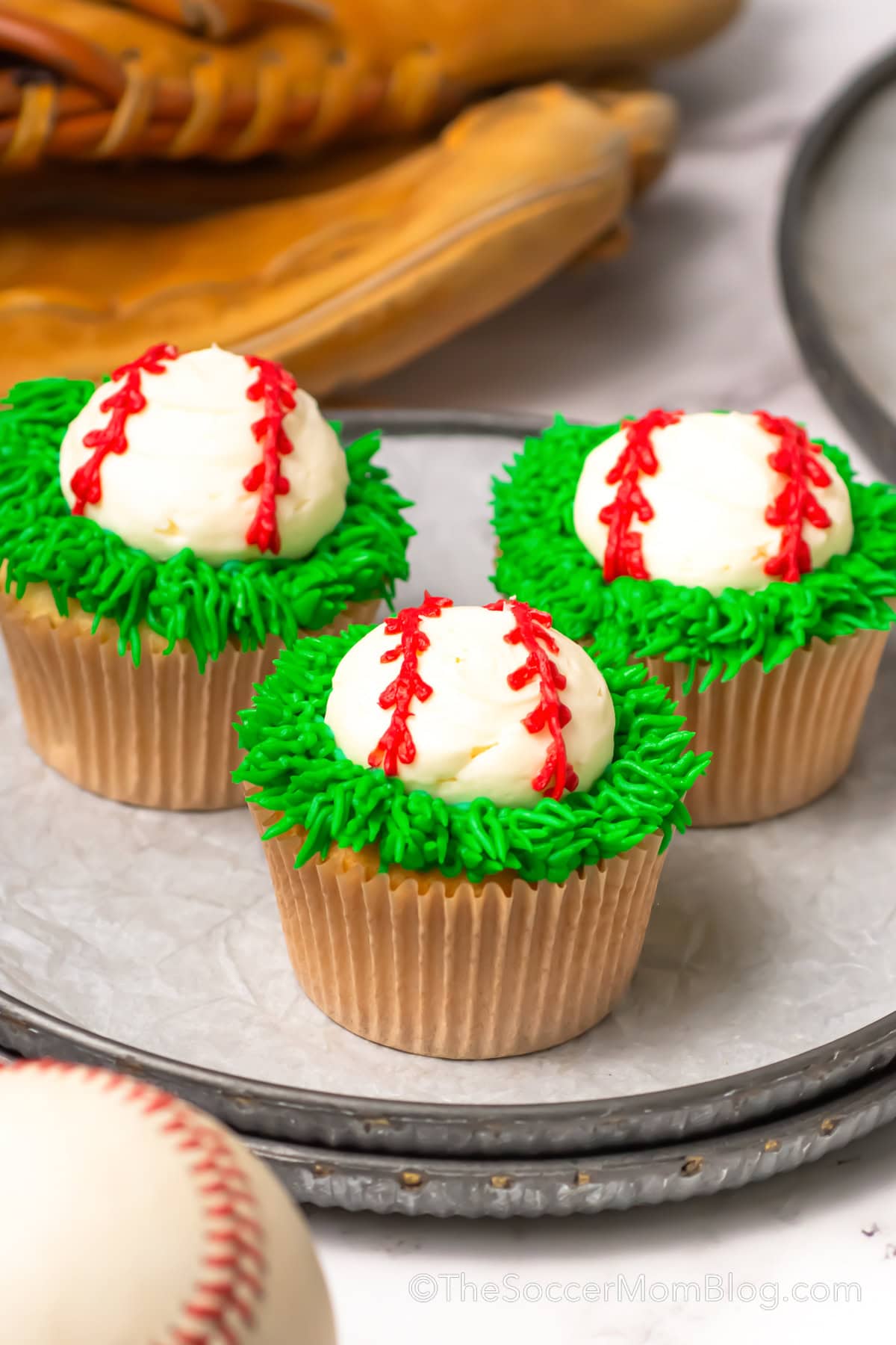Three Baseball Cupcakes on a parchment line baking sheet.