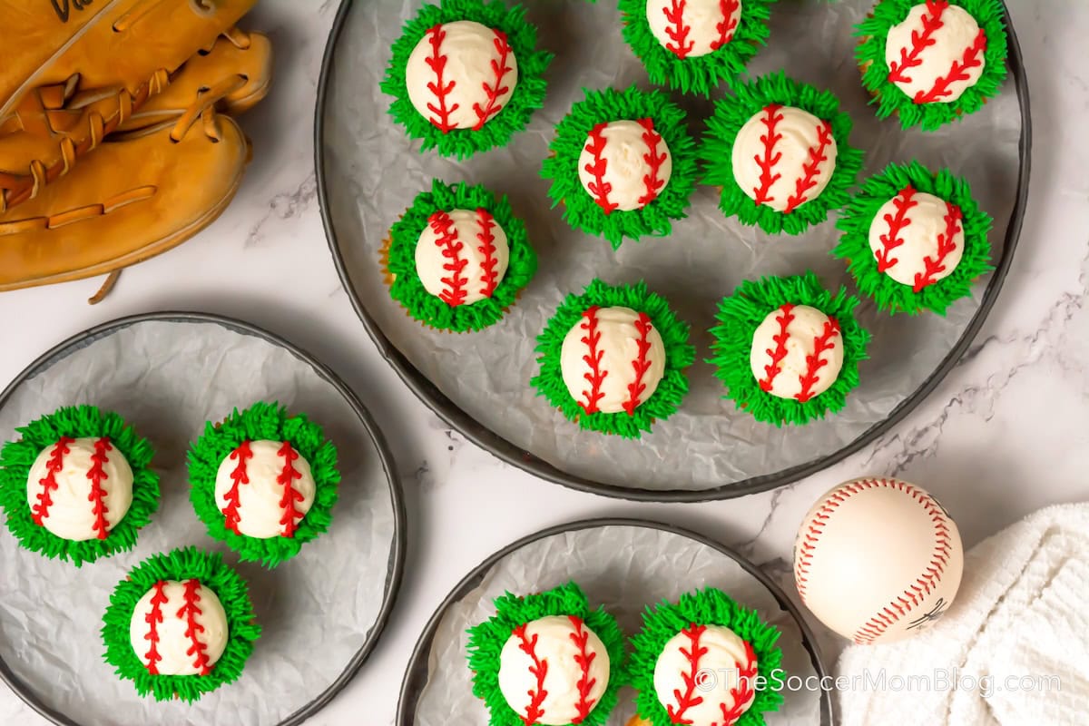 Three serving trays of Baseball Cupcakes on a table with a baseball glove and ball.