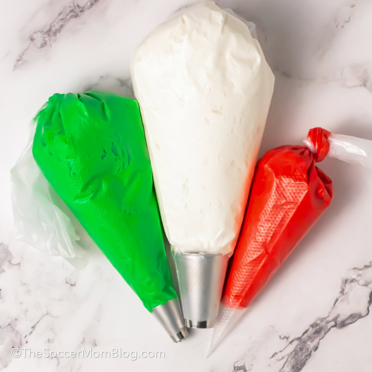 Three piping bags filled with red green and white frosting.