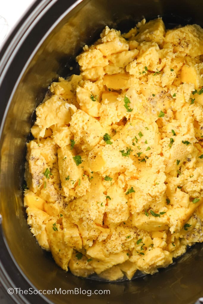 A slow cooker with scrambled eggs in it.