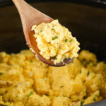 A wooden spoon with slow cooker scrambled eggs on it.