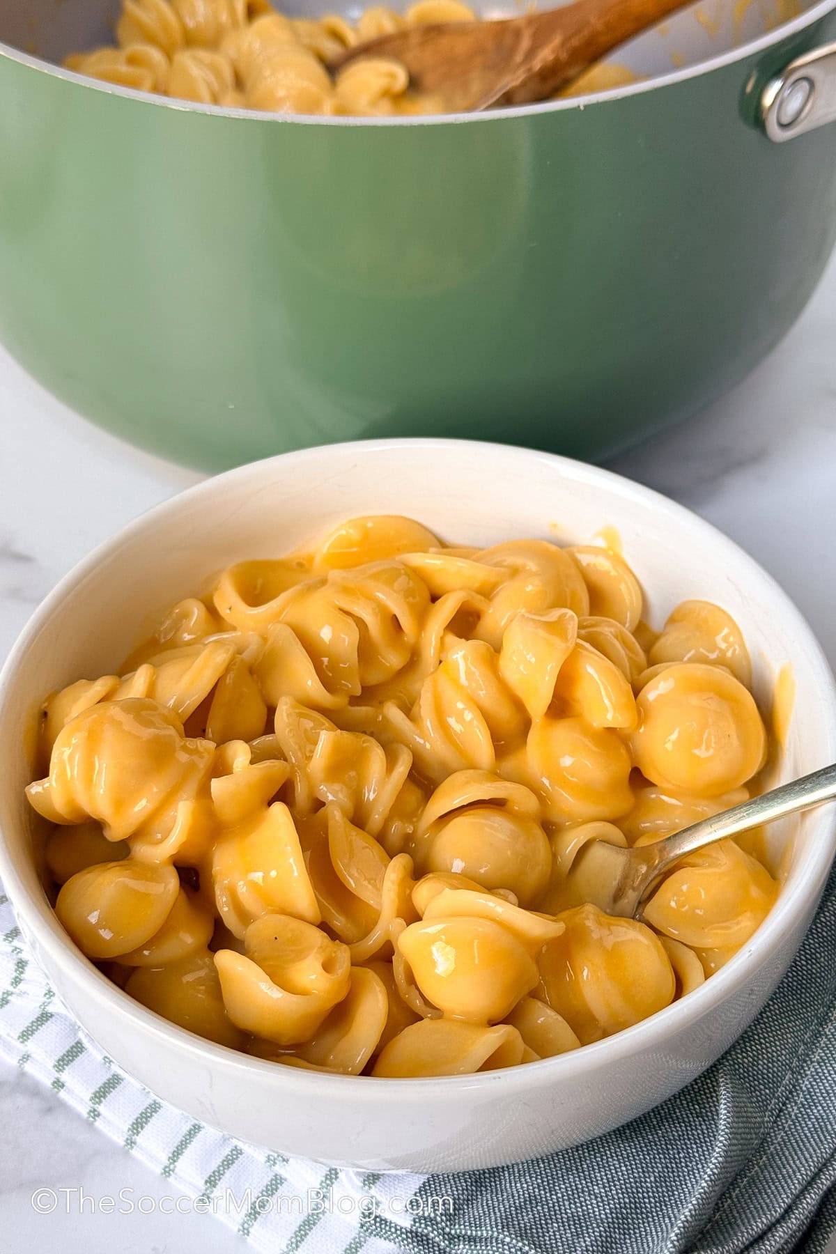 bowl of macaroni and cheese with a pot in background.