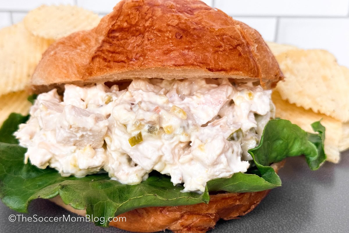 chicken salad sandwich on a croissant, served with chips.