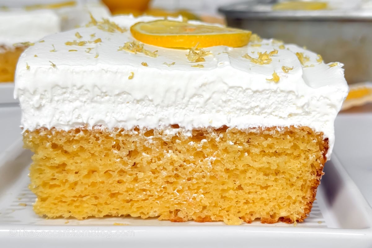 slice of lemon poke cake topped with white frosting.