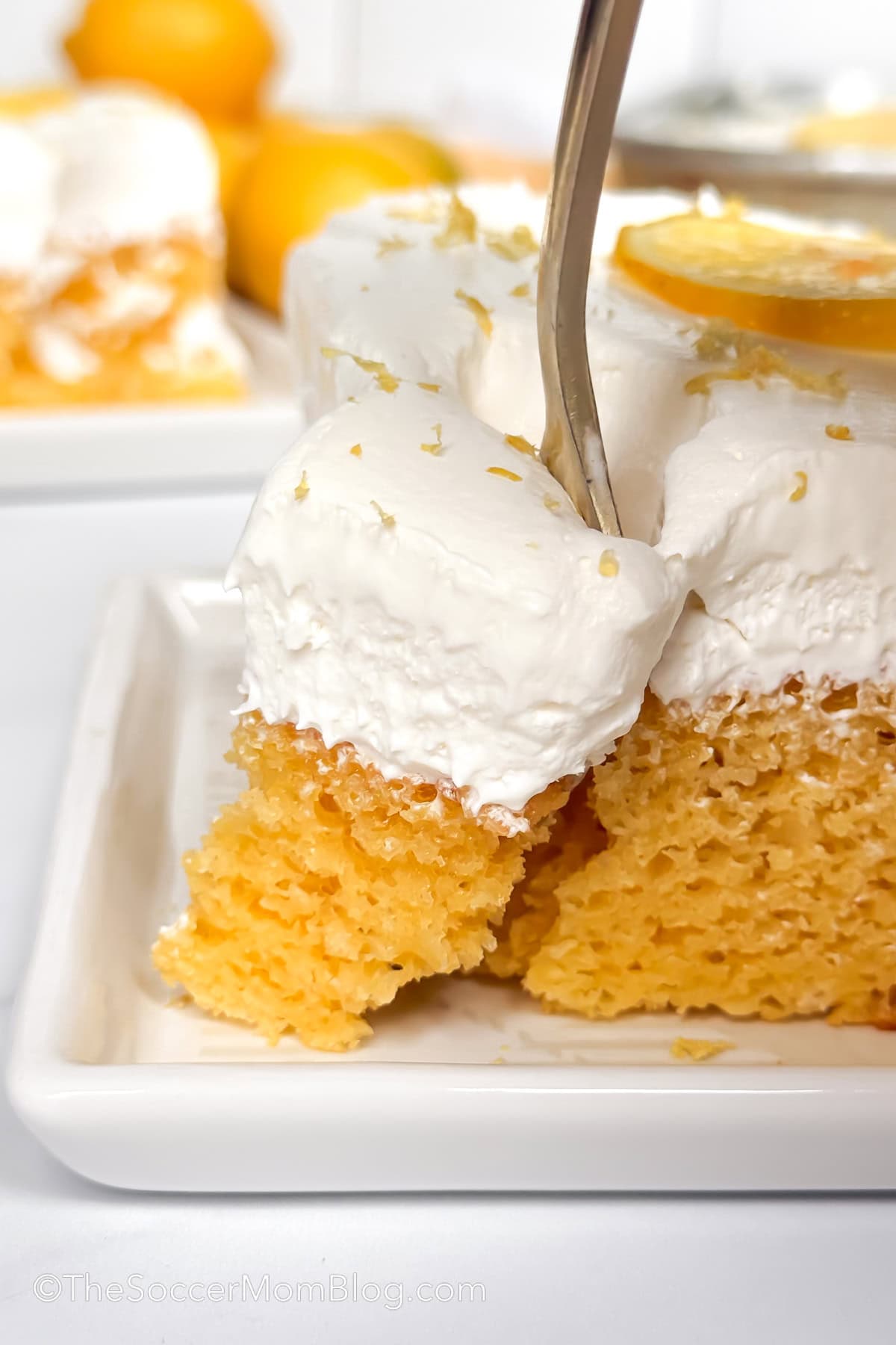 taking a bite of a lemon cake, with whipped topping frosting.