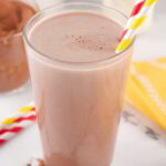 glass of chocolate milk with the chocolate drink mix powder in background.