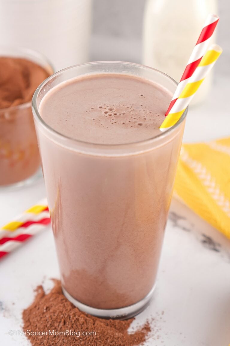 glass of chocolate milk with the chocolate drink mix powder in background.