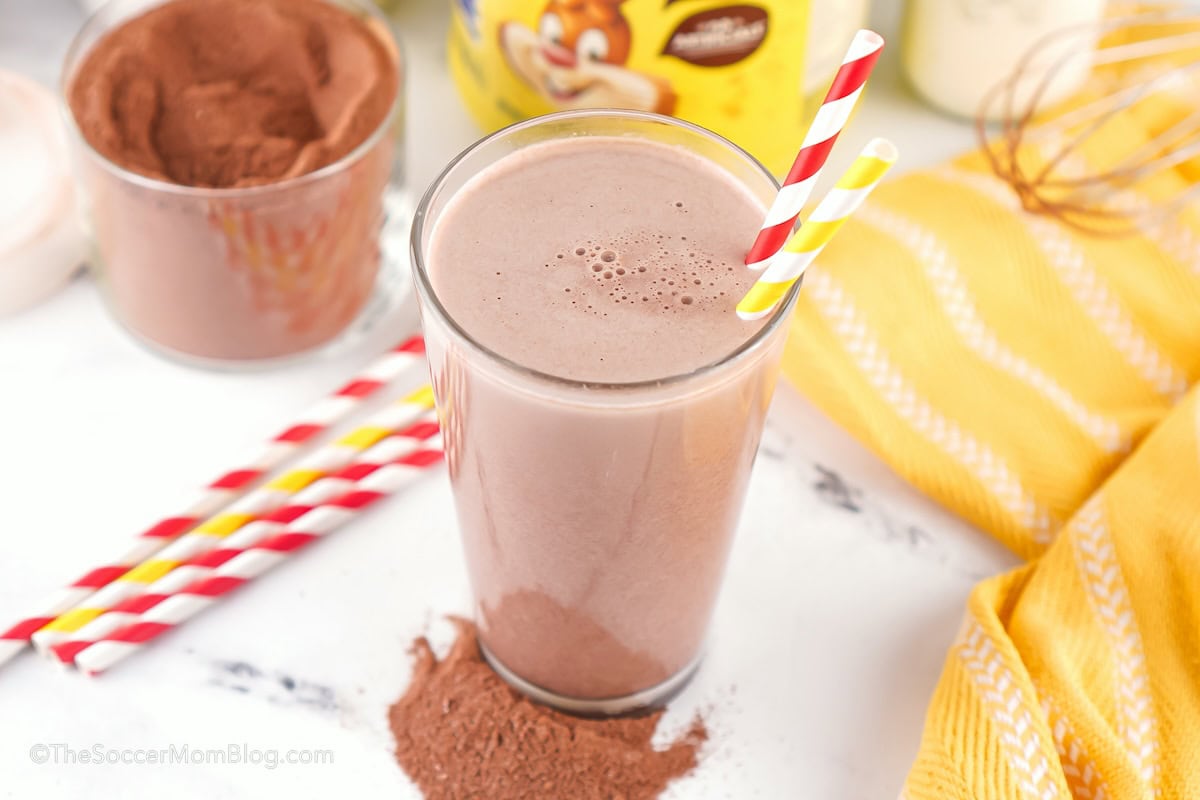 glass of chocolate milk with homemade Nesquik powder in background.