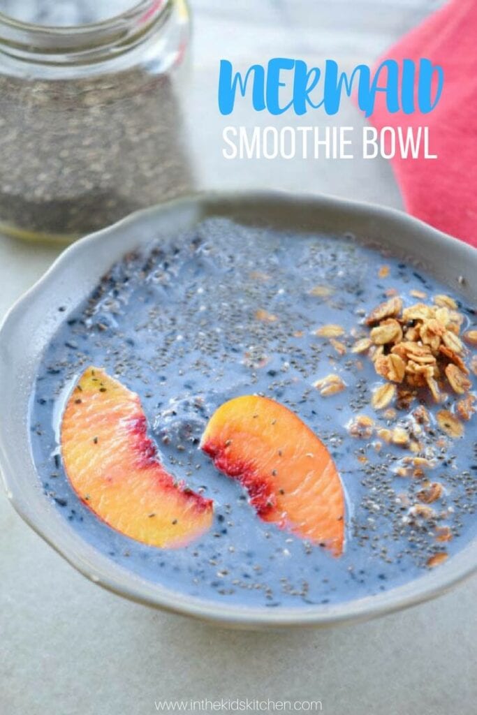 blue smoothie bowl topped with peach slices and granola.