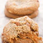 salted caramel cookies, one torn open to show meted caramel inside.