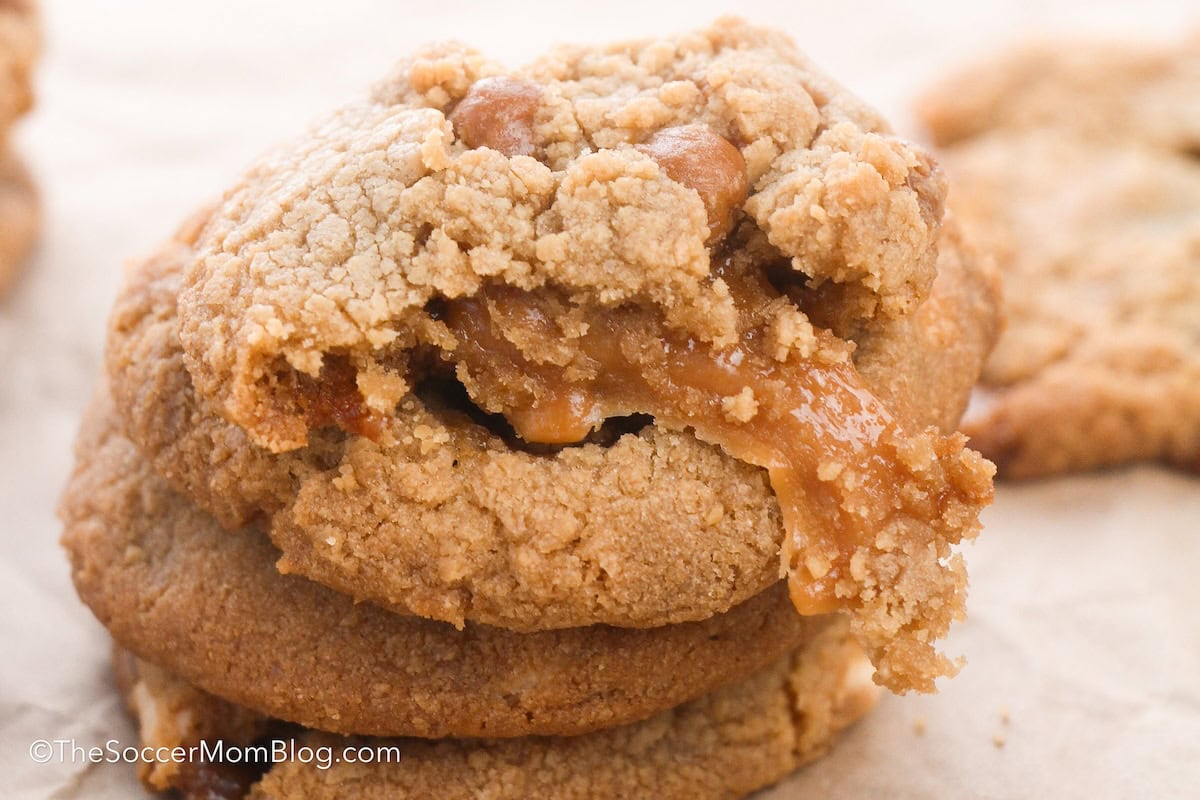 close up on a stack of caramel filled cookies, with the top one torn in half to show detail.