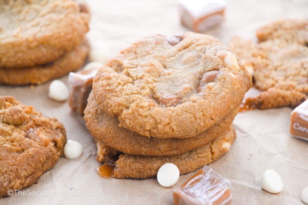 a stack of salted caramel cookies, surrounded by white chocolate chips.