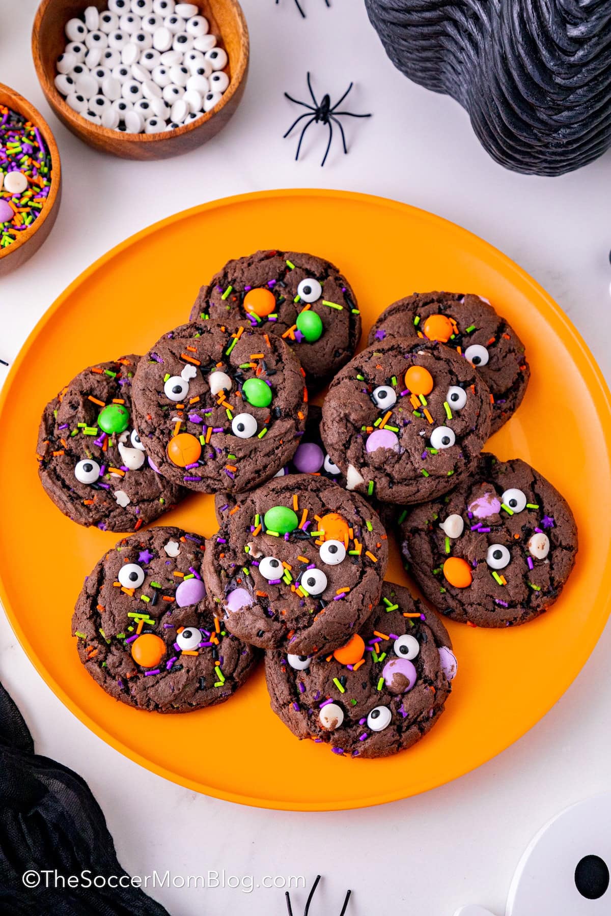 An orange plate piled with Chocolate Halloween Monster Cookies.