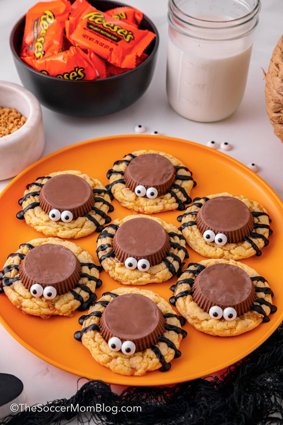 Plate of spider cookies made with Reese's cups, frosting, and candy eyes.