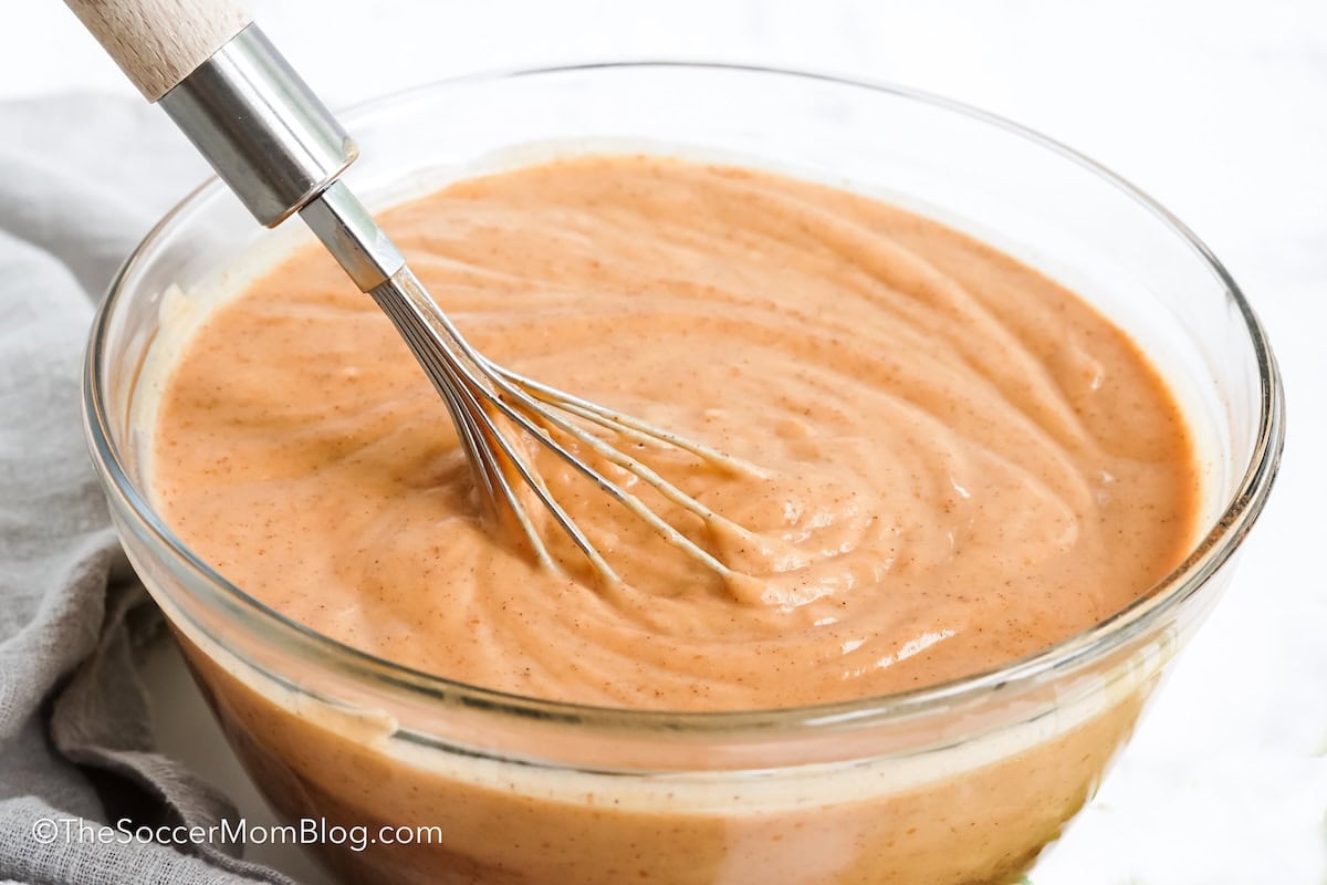 Pumpkin Pudding being mixed with a metal whisk in a glass bowl.