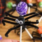 holding a lollipop decorated to look like a spider.